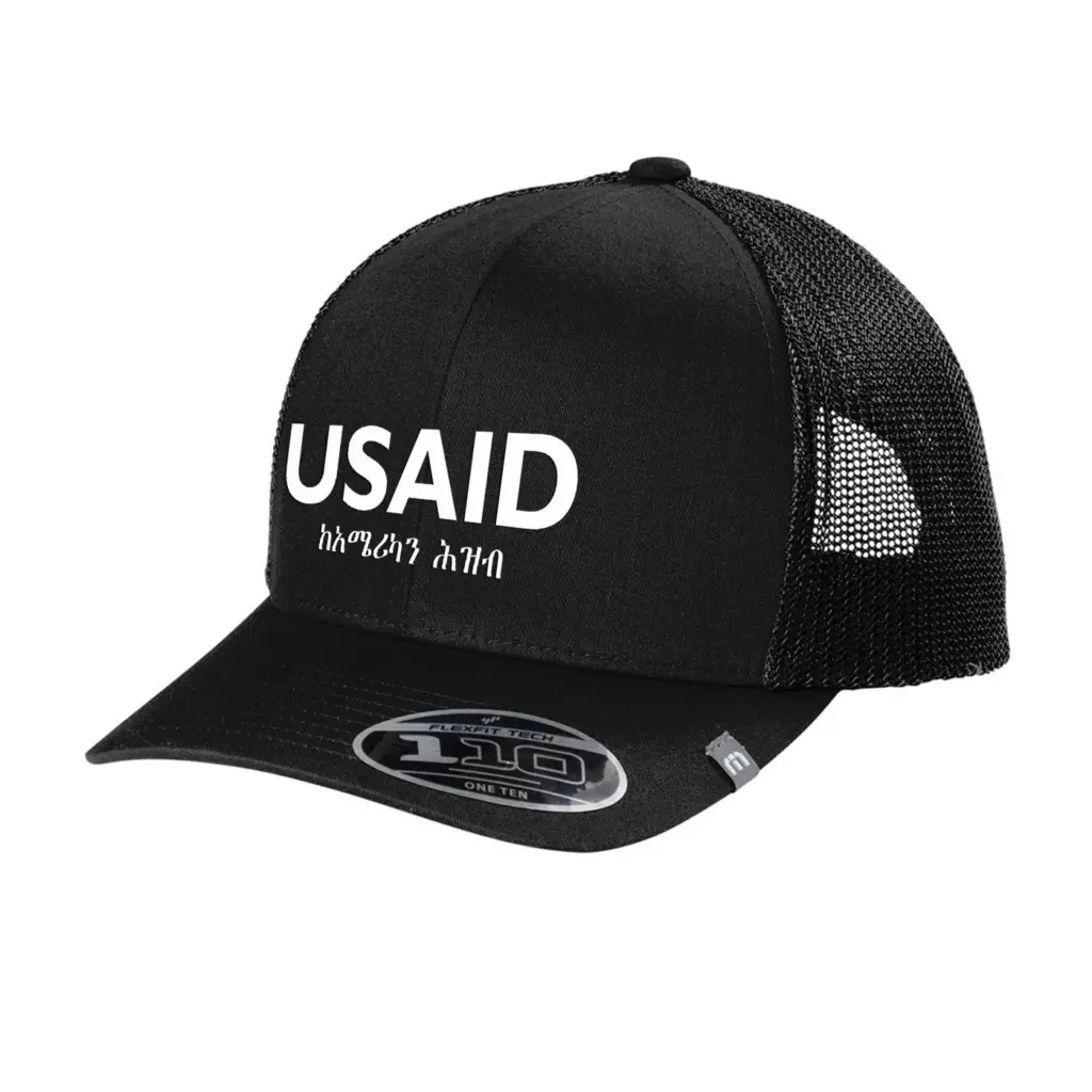 USAID Amharic - Embroidered New TravisMathew Cruz Trucker Cap (Min 12 pcs)
